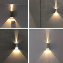Black pyramid-shaped LED wall sconce mounted on a wooden wall, displaying a rectangular light pattern.