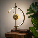Wireless charging clock lamp with LED light on a wooden table, featuring a lampshade and surrounded by houseplants.