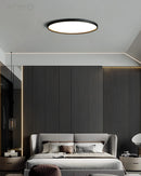 Black rimmed circular LED ceiling light with minimalist design, mounted on a white ceiling in a modern, comfortable interior setting.