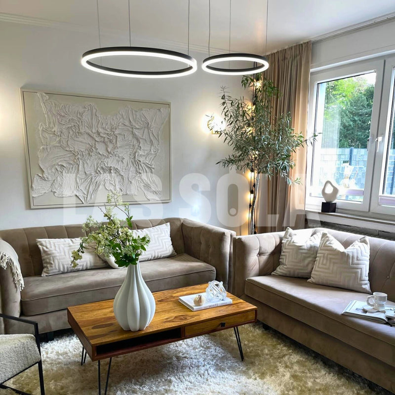 Circular LED Pendant Light in Gold Finish, Adjustable Height Chandelier hanging above a modern dining table with chairs, indoor plants, and large windows in a well-designed living space.
