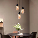 Modern industrial kitchen with a designer ribbed glass pendant light hanging above a wooden table, complemented by plants and stylish furniture.