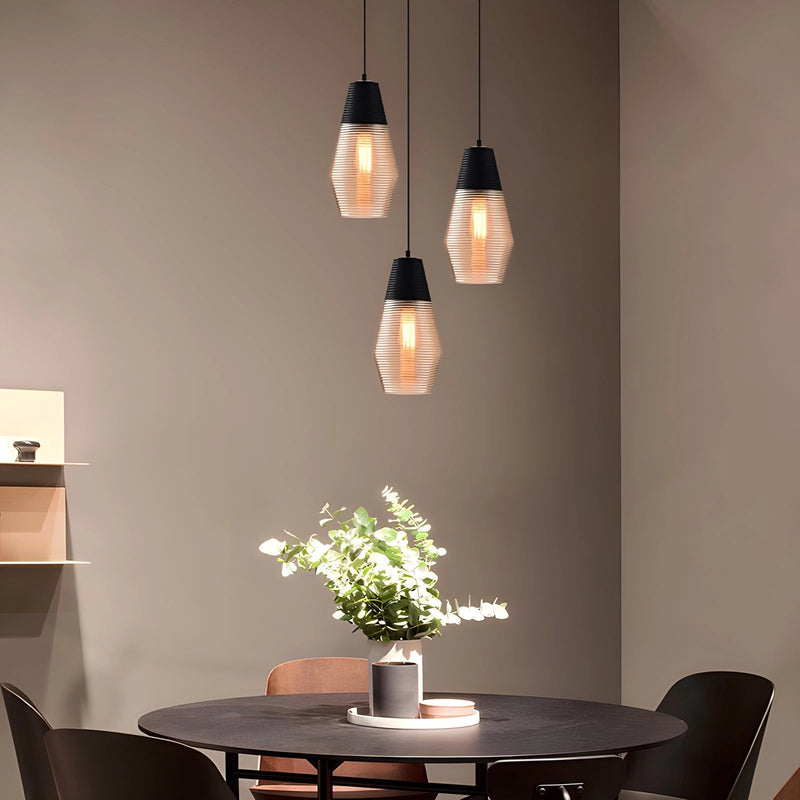 Modern industrial kitchen with a designer ribbed glass pendant light hanging above a wooden table, complemented by plants and stylish furniture.