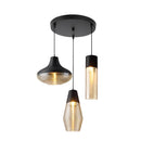 Modern industrial-style pendant light with three circular ribbed glass shades, featuring metallic accents, suspended over a wooden kitchen table.