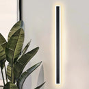 Minimalist LED Wall Sconce with sleek vertical rectangular light design, mounted on a wall near a houseplant.