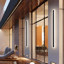 Minimalist LED wall sconce with a sleek vertical rectangular design mounted on a wooden wall in a modern interior setting.