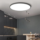 Minimalist round LED ceiling light in black, flush mount design, slim and energy-efficient, 37cm diameter, with switch-controlled color changeability, installed in a modern interior with wooden cabinetry and flooring.
