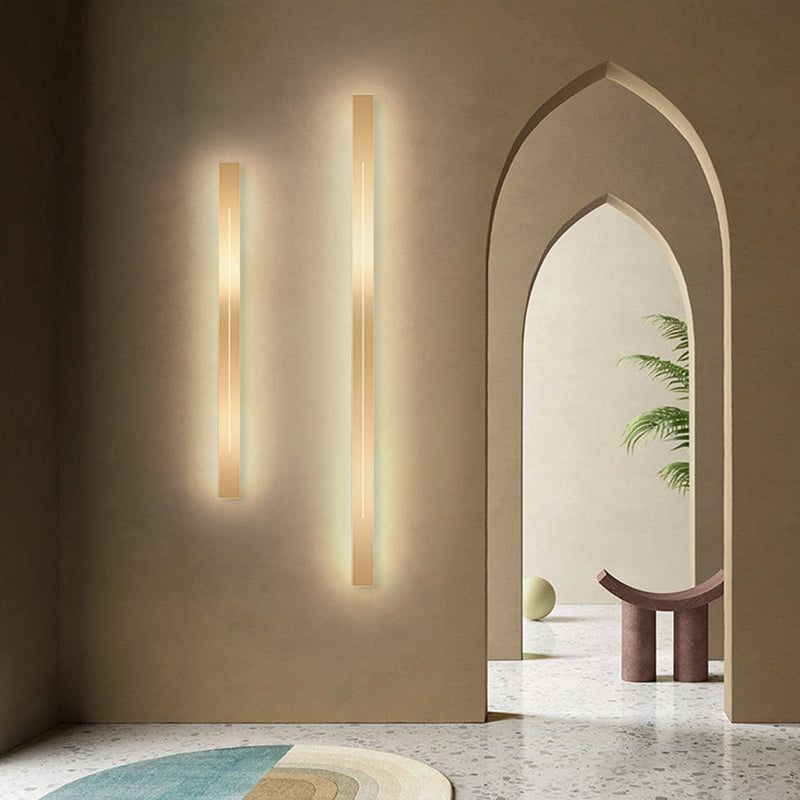 Minimalist Slim Gold Bar Pendant Necklace displayed on a wooden surface with a modern interior background featuring soft lighting and a plant.