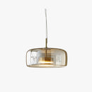 Modern glass pendant light with brass accents, elegant ceiling fixture, suspended from ceiling, featuring a combination of rectangular and circular metal elements, with a touch of beige and wood tones.