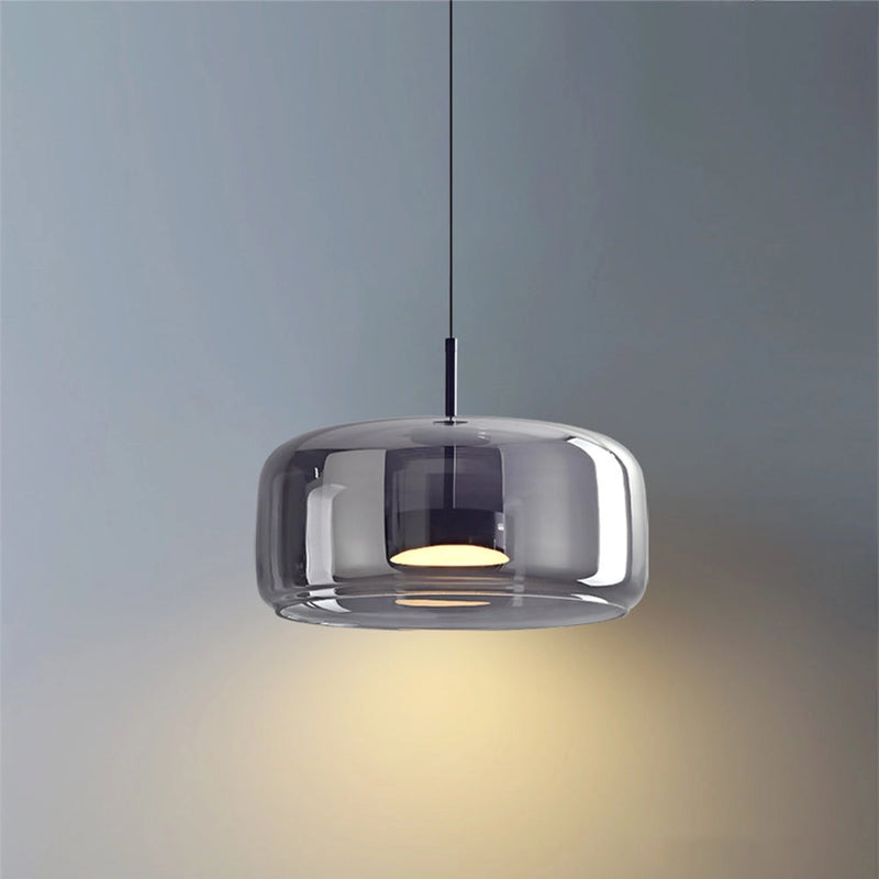 Modern glass pendant light with brass accents, elegant ceiling fixture featuring a sleek design, suspended from the ceiling with a mix of metal and glass materials.