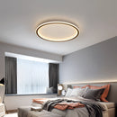 Modern LED ceiling light with dimmable feature, minimalist circular flush mount in black, installed in a stylish interior with grey and wood elements, textiles, and comfortable furnishings.