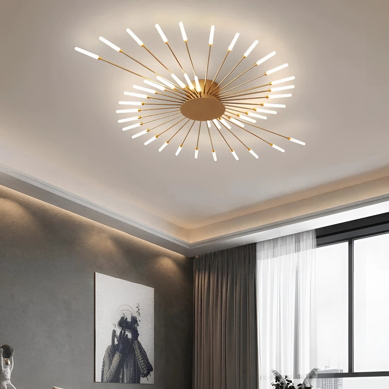 Modern starburst wall art in black and gold metal sculpture hanging on a wall, with light streaming through nearby windows and interior design elements such as plants and wooden furniture visible.