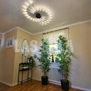 Modern Starburst Wall Art - Mid-Century Black Gold Metal Sculpture hanging on a wall near a window with indoor plants.