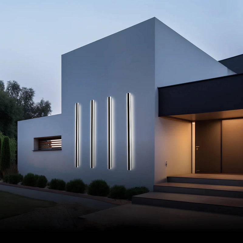 Slim Vertical LED Wall Sconce mounted on the exterior facade of a modern building with a minimalist design, surrounded by plants and a clear sky.