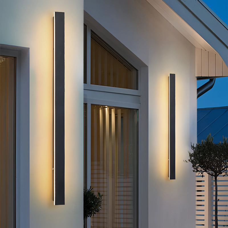 Slim vertical LED wall sconce, minimalist design, mounted on a wooden wall, next to a window with houseplant and flowerpot, 200CM dimmable version.