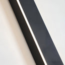 Minimalist slim vertical LED wall sconce mounted on an exterior wall at night, illuminating the area with a soft, waterproof light.