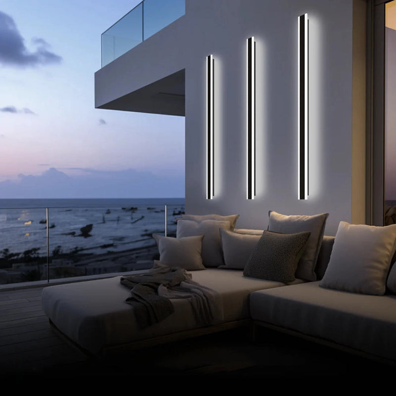 Slim Vertical LED Wall Sconce mounted on the exterior of a modern building with a clear sky and scattered clouds in the background.