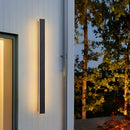 Slim Vertical LED Wall Sconce - Minimalist Waterproof Light, 150CM Dimmable, mounted on an exterior wall with a background of sky and building, accompanied by plants and wooden elements.