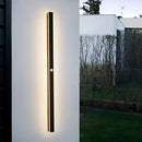 Slim Vertical LED Wall Sconce mounted on a modern building facade, surrounded by sunlight and trees, with a minimalist design that includes dimmable motion sensors.
