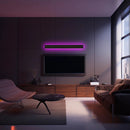 Minimalist waterproof slim vertical LED wall sconce illuminating a modern living room with a purple couch, wooden flooring, and a television near a window.